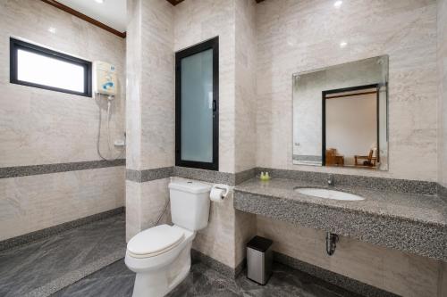 a bathroom with a toilet and a sink and a mirror at Onnicha Hotel Phuket in Phuket