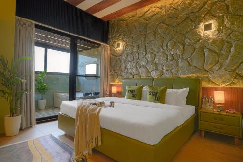 a bedroom with a large bed and a stone wall at Stay XO - A Luxurious 3BHK Villa in Panchkula in Panchkula