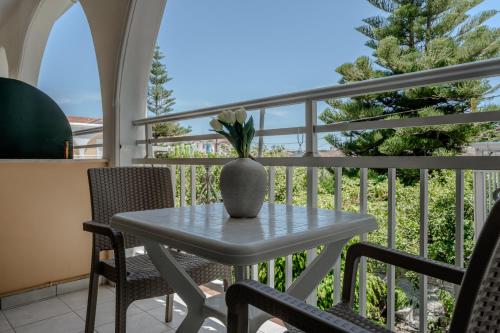 a table and chairs on a balcony with a vase on it at Domus Alta in Tsilivi