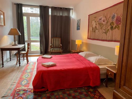 a bedroom with a bed with a red blanket on it at Domaine du Chesne in Salbris
