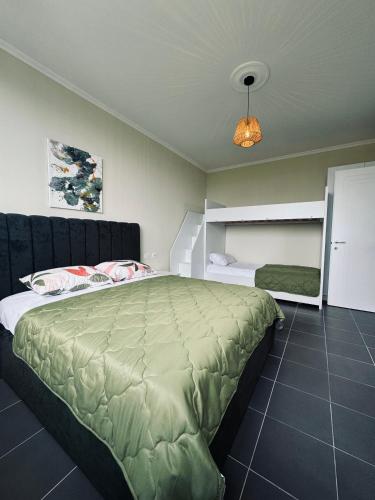 a bedroom with a large bed with a green comforter at Andrra Apartment - Talea Coast in Lezhë