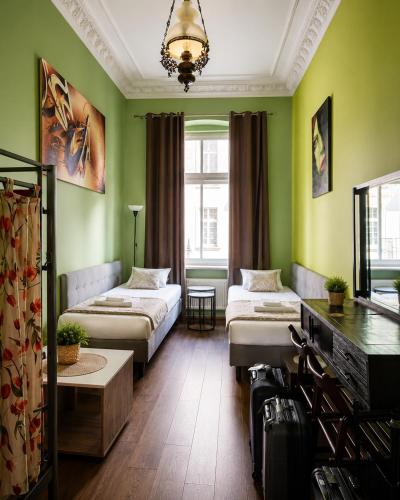 a green room with two beds and a table at Babel Hostel, Dworzec PKP, Rynek in Wrocław