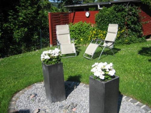 巴特科尼希的住宿－Haus Meckbach，院子里放着鲜花,放着两把椅子和一把椅子