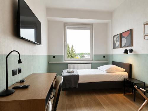 a bedroom with a bed and a desk and a window at Pokoje & Bistro Mielec in Mielec