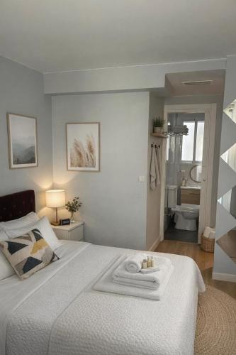 a white bedroom with a bed and a bathroom at EL PRINCIPE in Zaragoza