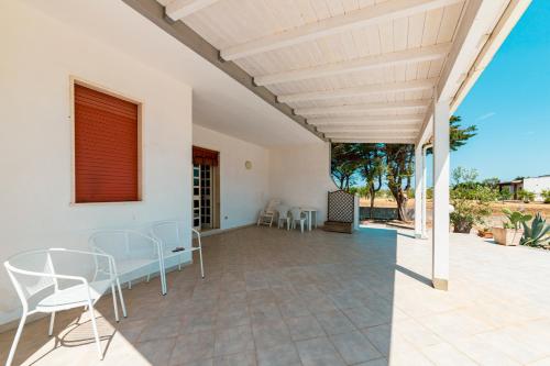 a patio with white chairs and a table at Baglivi's Flat in Torre Specchia Ruggeri