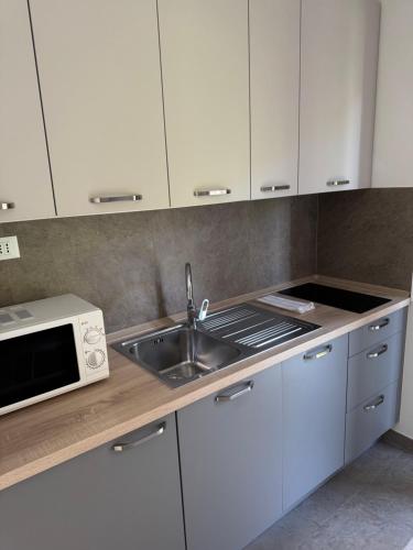 a kitchen with white cabinets and a sink and a microwave at Apartments Medora in Rovinj