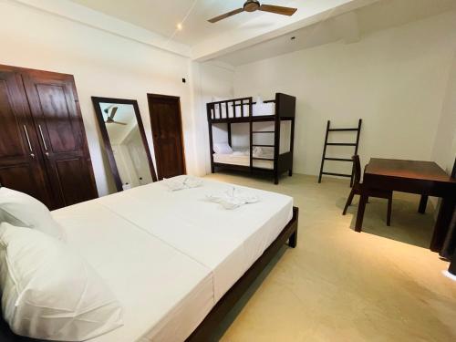 a bedroom with a bed and a desk and a bed and a chair at Surf Arugam in Arugam Bay