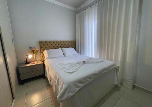 a white bedroom with a bed and a window at 474 Flats e Suítes Standard in Ipatinga