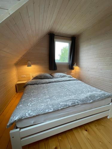a bed in a small room with a window at Aurora - Domki całoroczne nad morzem w Dziwnówku in Dziwnówek