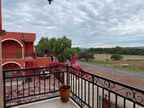a balcony of a red building with pink flowers at Hotel Estancia Bugambilias in San Diego de la Unión