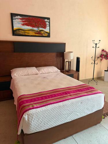 a bedroom with a bed with a painting on the wall at Hotel Estancia Bugambilias in San Diego de la Unión
