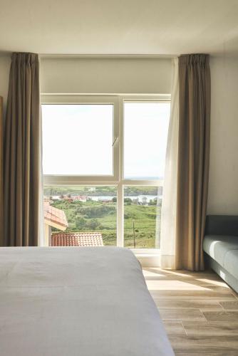 a bedroom with a bed and a large window at Alima Surf & Hotel in Ajo