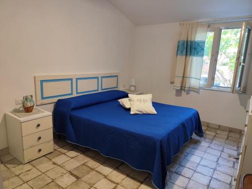 a bedroom with a blue bed and a window at Casa Contadina in Oristano