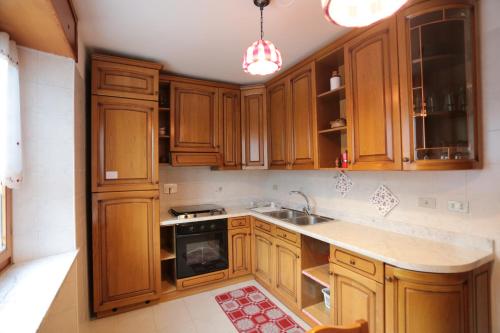 a kitchen with wooden cabinets and a sink at Beauregard apartment in Aosta