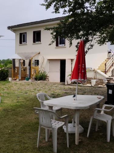 a table with a red umbrella and chairs in front of a house at Les pieds dans l'eau Tente transparente in Fleurville