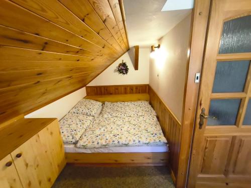 a small bed in a room with a wooden ceiling at Pension V Doubí in Slavče