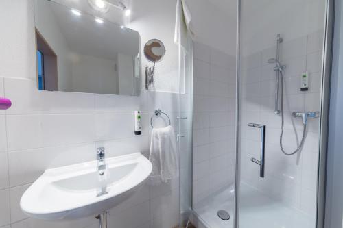 a white bathroom with a sink and a shower at Friends Hotel Bad Salzuflen in Bad Salzuflen