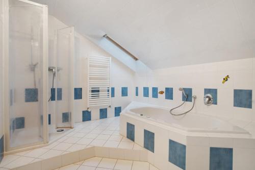 a white bathroom with a tub and a shower at Herrenhaus Carolinenhof in Groß Plasten