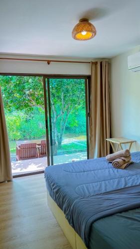a bedroom with a bed and a large sliding glass door at มาแคมป์ ชะอม in Ban Bung Mai