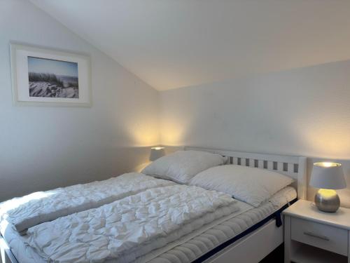 a bedroom with a white bed with two lamps at Ferienwohnung in Burhave in Burhave