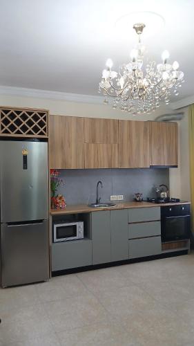 a kitchen with a stainless steel refrigerator and a chandelier at Гостевой дом 300м от моря "Кавказская пленница" in Kobuleti