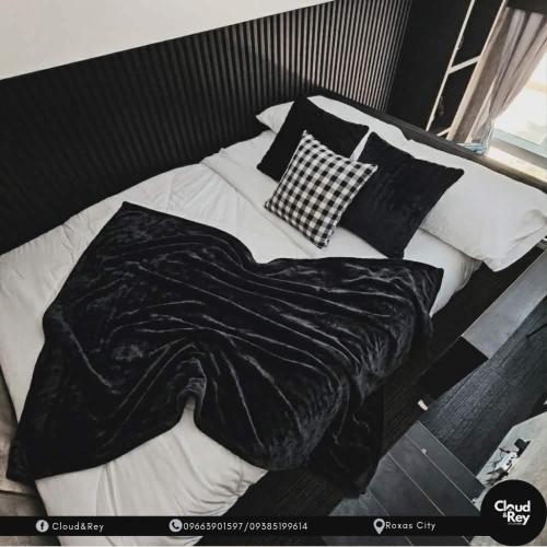 a bed with black and white sheets and pillows at Cloud&Rey Rentals in Roxas City