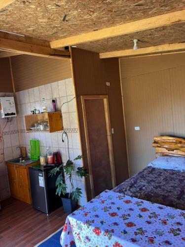a bedroom with a bed and a kitchen in a room at Cabañas y tinajas in Ancud