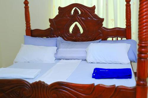a bed with a wooden headboard and white pillows at standalone in Fort Portal