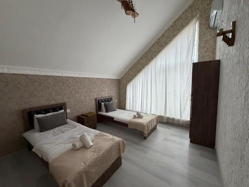 a bedroom with two beds and a large window at Gabala Home in Gabala