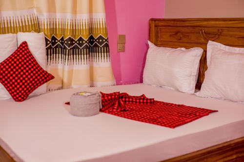 a bed with red and white pillows on it at Olivia Green Lodge in Arusha