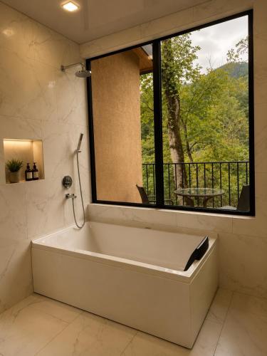a bath tub in a bathroom with a large window at Wald Hotel Lagodekhi in Lagodekhi