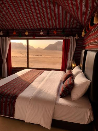 a bed in a room with a view of the desert at Starry Nights Camp in Wadi Rum