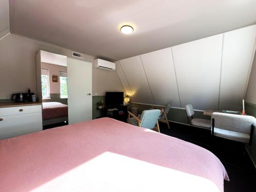 a bedroom with a bed and a desk and chairs at B&B Wetterwille in Opeinde