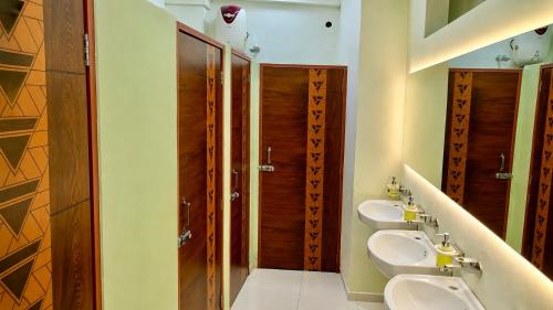 a bathroom with three sinks and three toilets at VELORA DORMs in Ujjain
