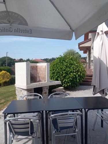 two tables and chairs under an umbrella on a patio at Toxiños Lavacolla in A Coruña