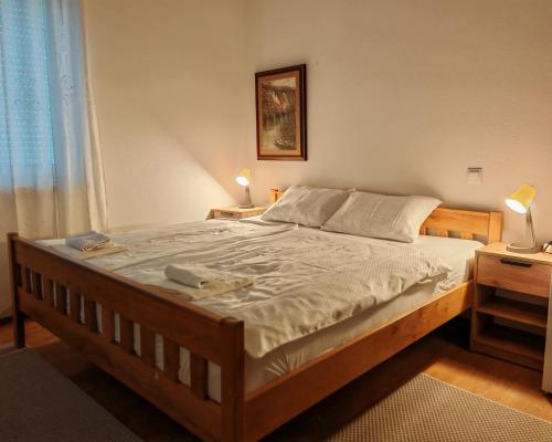 a bed in a bedroom with two lamps and a window at Apartments Vesna in Slunj