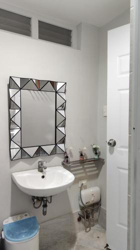 a white bathroom with a sink and a mirror at Mactan Cozy Hub Amani Grand in Lapu Lapu City