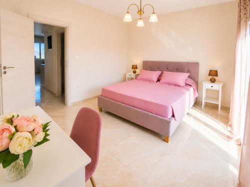 a bedroom with a bed and a table with a vase of flowers at Ma Maison Rose in Kremasti