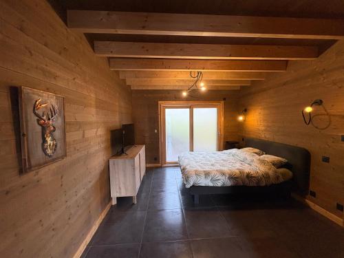 a bedroom with a bed in a wooden room at Chalet du paradis in La Bresse