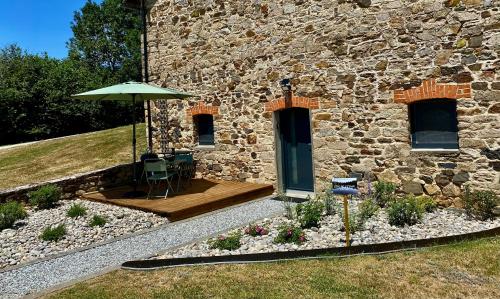a patio with an umbrella next to a stone building at Maison Gîtes de l'étang caché in Chamboulive