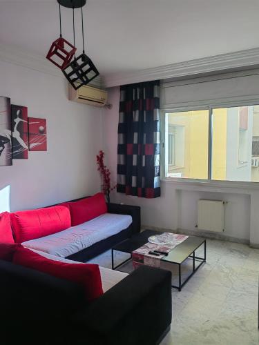 a living room with a red couch and a window at Coquet ac accès autonome in El Aouina Station