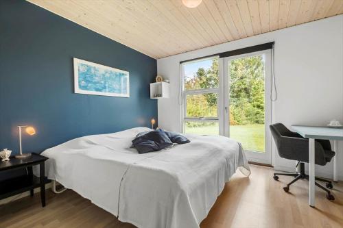 a bedroom with a bed and a desk and a window at 8843-Glesborg-Lyngtoften-34 in Glesborg