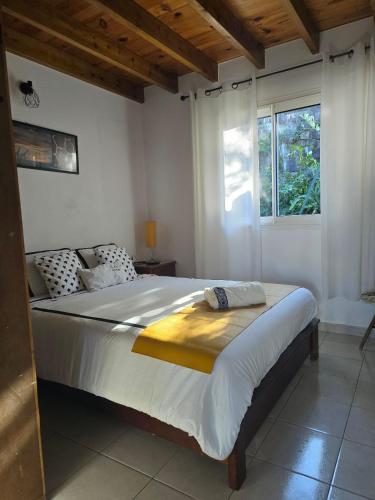 a bedroom with a large white bed with a window at Ti kaz Annah in Le Tampon