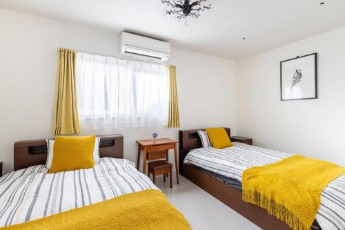 a bedroom with two beds with yellow blankets and a table at nonon in Osaka