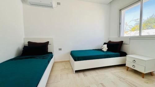 a bedroom with two beds and a window at Corail in Djerba