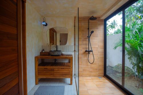 a bathroom with a shower with a sink and a mirror at Arcana Wellness Center - Adults Only in Ko Phangan