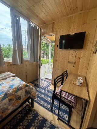 a bedroom with a bed and a table and a television at Wooden house in Kutaisi