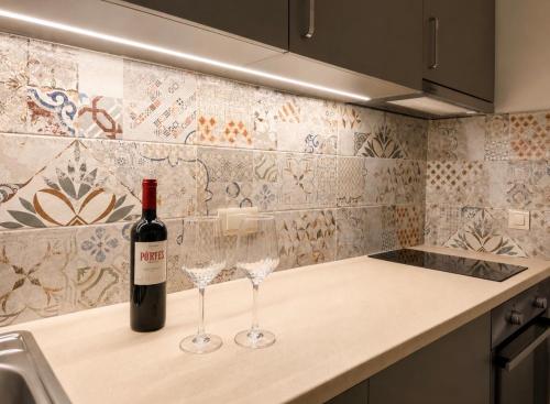 a bottle of wine sitting on a counter with two wine glasses at ΕΝ ΑΛΩ Residences in Kiveri