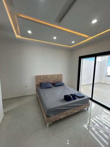 a bedroom with a bed in a room with a window at Villa blanca in Al Maqārisah